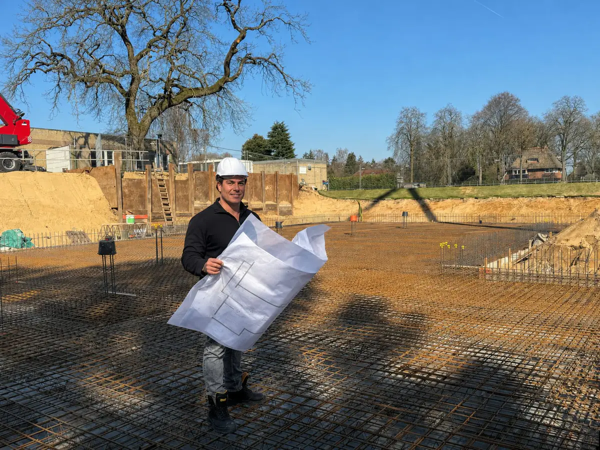 Kwaliteitsborger op de bouwplaats met een bouwtekening in zijn handen