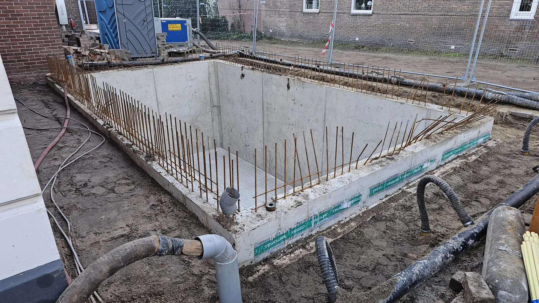Betonnen funderingsbak met aansluitingen en uitstekende wapening tijdens de bouw